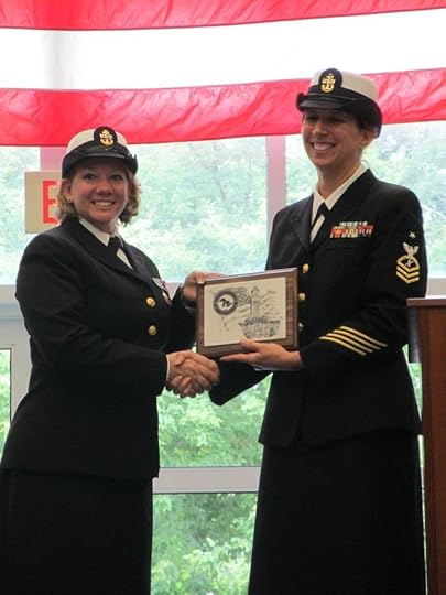 A female chief petty officer jointly holding a plaque with a female senior chief petty officer