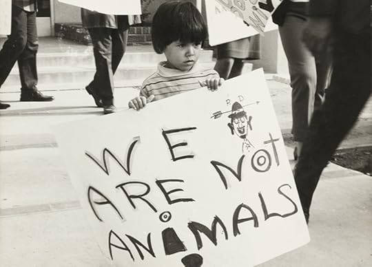 A young boy holds a sign that reads, 