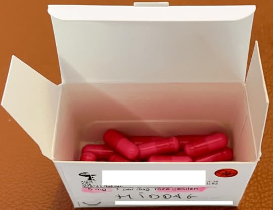 Een open doos met roze capsules van 5 mg, mogelijk medicatie, met een etiket dat de inhoud en dosering aangeeft.