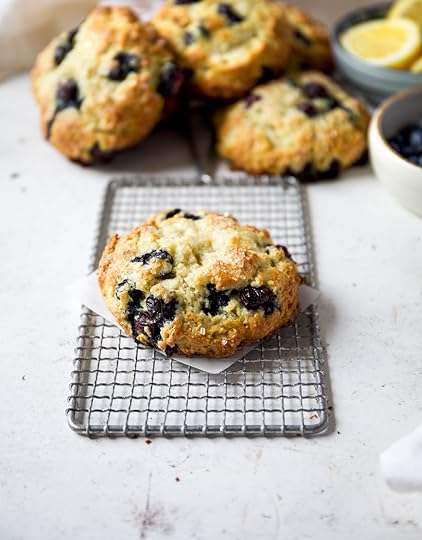 A big giant bronzed blueberry scone on top of a vintage cooling rack on a white surface.