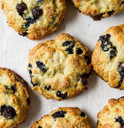 Overhead shot of a bunch of blueberry scones that are baked to golden perfection on a white parchment surface.