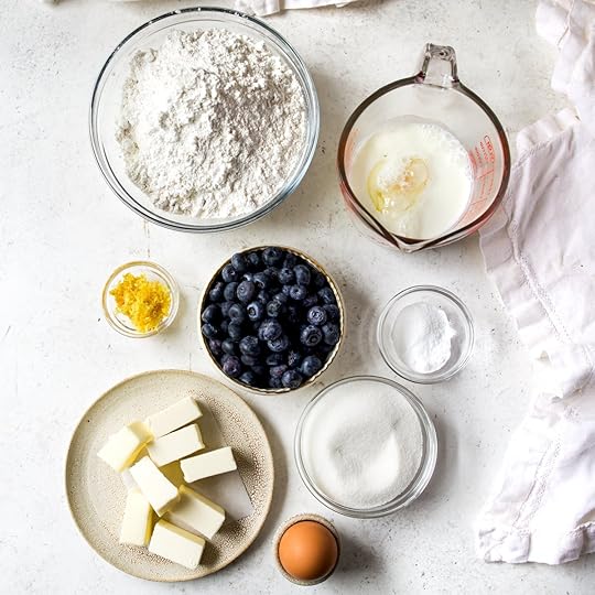 In bowls and liquid measuring cups are all of the ingredients to make blueberry scones.