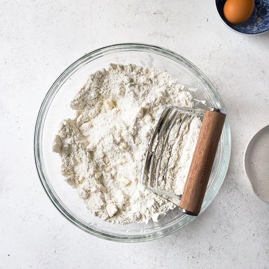A pastry blender sitting in a bowl with flour.