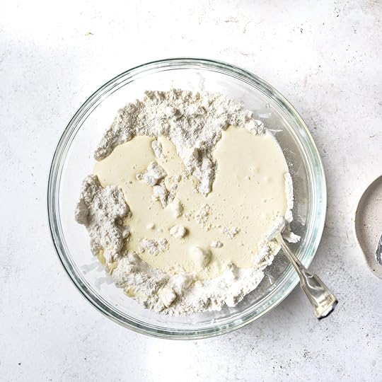 Buttermilk pooled on top of a flour mixture in a glass bowl.