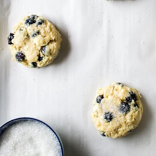 Two scones on parchment paper with sugar over the top just before baking.