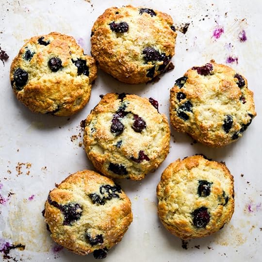 Blueberry lemon scones on a messy piece of parchment paper stained with blueberries.