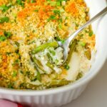 close up of green bean casserole with spoon inserted in the baking dish.