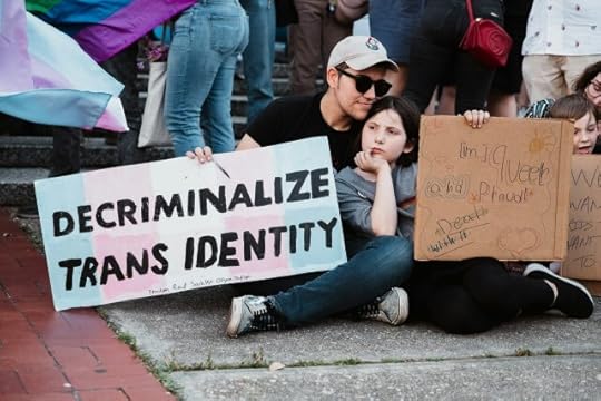 Protesters with a sign reading “Decriminalize Trans identity.” Blaming “The Other” Is a Distraction