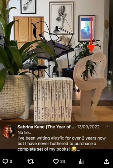 Social media post by Sabrina with a photo of a room with paperbacks of Sabrina Kane in the front and a white stature of a woman in the background