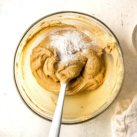 Leavening on top of cookie dough and a light blue spatula in a bowl.