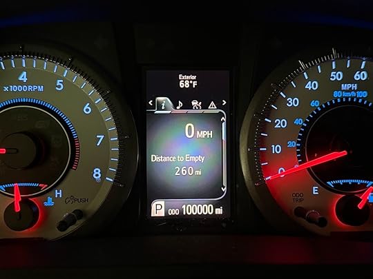 The image shows a car dashboard with three main displays. On the left is a tachometer indicating engine speed in RPM, with the needle pointing to zero. In the center is a digital display showing the exterior temperature as 68°F, a speed of 0 MPH, and a distance to empty of 260 miles. The odometer reads 100,000 miles. On the right is a speedometer with the needle also pointing to zero.
