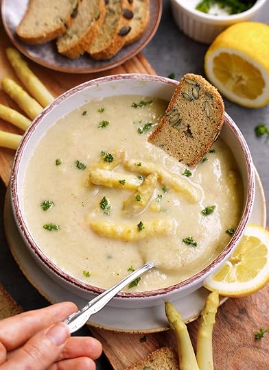 vegan cream of asparagus soup in bowl with piece of bread and spoon