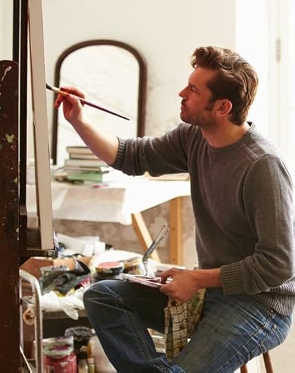 This may contain: a man sitting in front of a easel holding a paintbrush and looking at something