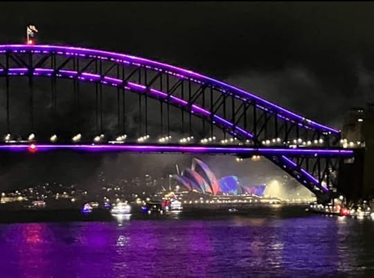 Sydney Harbour turns bright purple, reflecting the Sydney Harbour Bridge and Sydney Opera House illuminated during the Vivid Sydney lightshow.