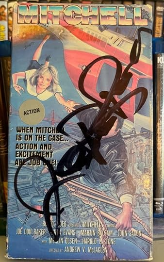 VHS copy of Mitchell. It depicts Baker hanging from a ladder next to a helicopter, and holding a lady with his other arm. In big, thick, black sharpie, is it signed Joe Don Baker.