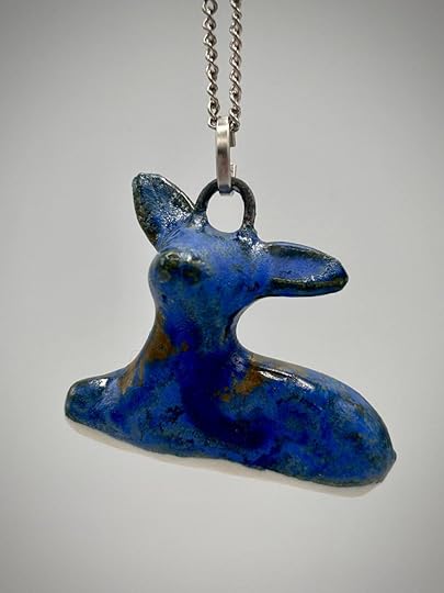 A blue ceramic deer pendant hanging from a silver chain.