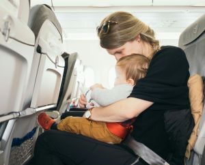 Woman with infant on lap while flying with kids