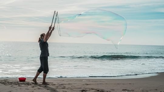 A person blowing a giant bubble on a beach. You find, make, and/or take joy.