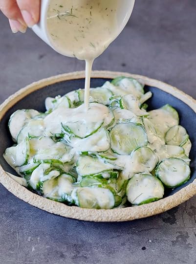 Pouring creamy dill dressing over German cucumber salad