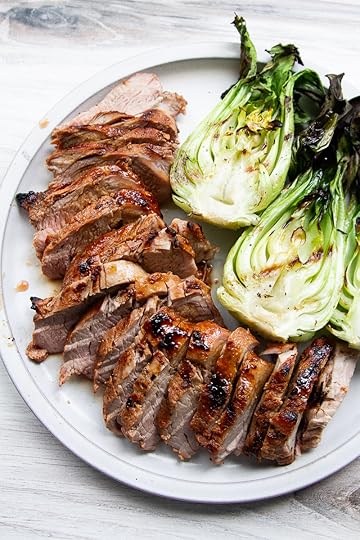 Sliced pork tenderloin on a plate with grilled bok choi.