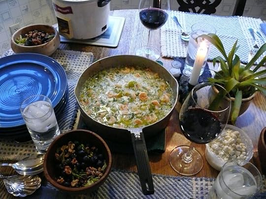A saucepan of shrimp etouffee on the table with other table settings.