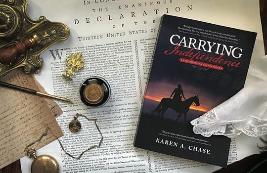 The novel, Carrying Independence, is laying on the Declaration, along with a pocket-watch, ink, and other vintage pieces from 1776.