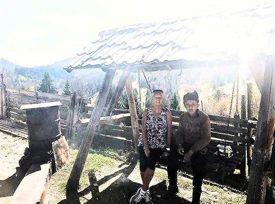 Janice Horton and A farmer sitting with his artisan cheese smoker and selling his fresh cheeses in rural Romania.