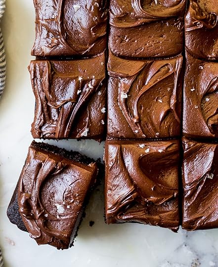 Overhead view of rich chocolate sheet cake slices topped with creamy chocolate buttercream frosting and a sprinkle of flaky sea salt, one slice removed, easy dessert recipe.