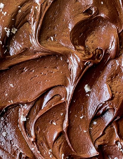 Close-up of rich and creamy homemade chocolate buttercream frosting with visible swirls and flaky sea salt sprinkles, great for cakes, cupcakes, and piping.