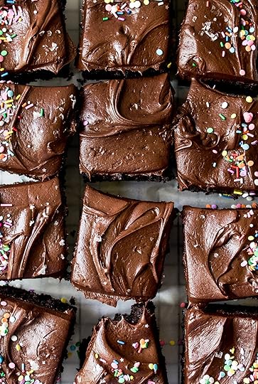 Overhead close-up of multiple slices of rich chocolate sheet cake, generously frosted with creamy chocolate buttercream, some squares adorned with vibrant rainbow sprinkles, others with flaky sea salt, showcasing a delicious homemade dessert recipe.