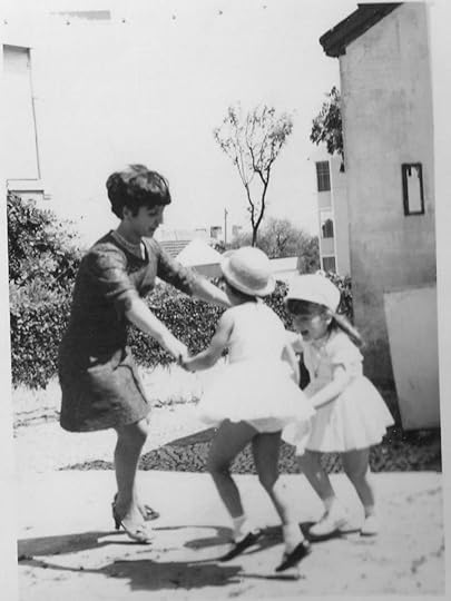 Young woman dancing with two little girls wearing white.