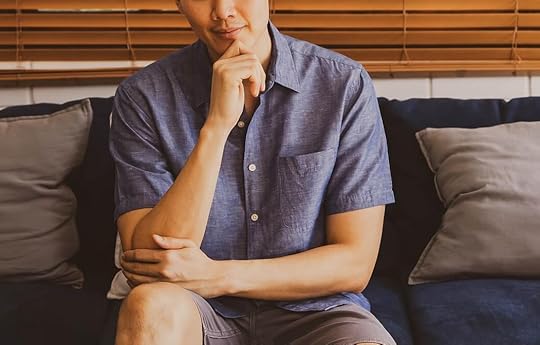 Thoughtful Asian man sitting on a couch touching his chin with his hand. ADHD perfectionism can be hard to overcome on your own. with the support of perfectionism treatment in Houston, TX you can learn how to effectively cope.