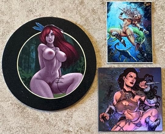 A circular coaster with a black border. Vanya is in the center, nude, with flowing red hair. The stick is rectangular and shows Vanya fighting a dinosaur with her knife underwater. The magnet is square and shows Vanya crouched in a defensive position with her knife.