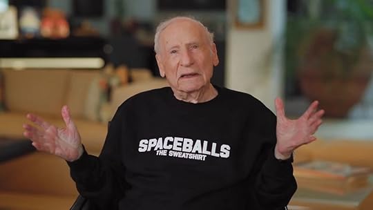 Mel Brooks with his arms held out wide with a Spaceballs The Sweatshirt on