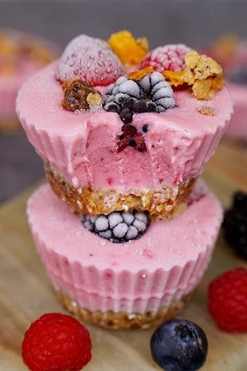 Close-up two pink frozen yogurt cup with a bite taken out, showing a creamy berry layer and a chewy base of dates, oats, and nuts