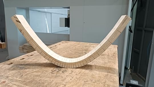 A parabola made out of kerf-bent plywood. The exposed edge shows cuts spaced tighter in the center.