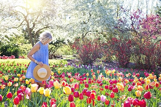 Happy woman walking through a patch of colorful tulips on a sunny day. Learn to break free from your perfectionistic thinking and start healing with the help of perfectionism treatment in Houston, TX.