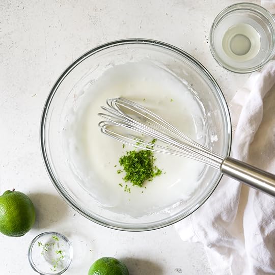 Whisking fresh lime zest into easy homemade lime glaze in a glass bowl.