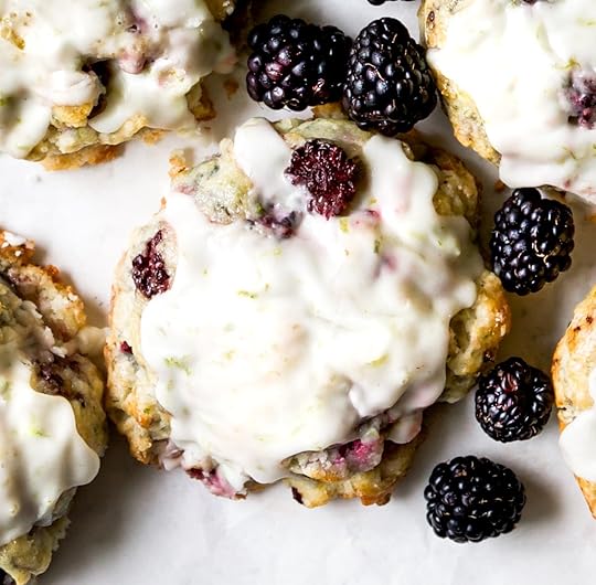 Close-up of fluffy blackberry scones generously drizzled with homemade lime glaze.