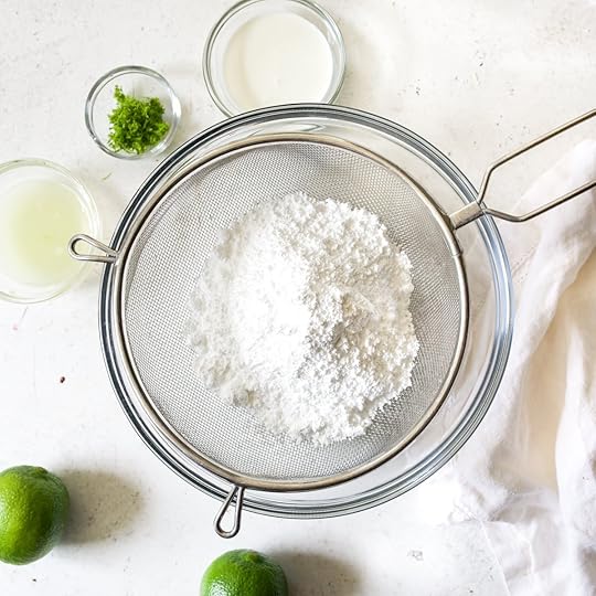 Sifting confectioners' sugar into a bowl with a sieve for easy lime glaze.