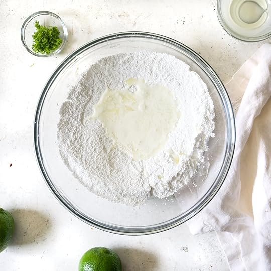 Confectioners' sugar and liquid ingredients for easy lime glaze in a glass bowl