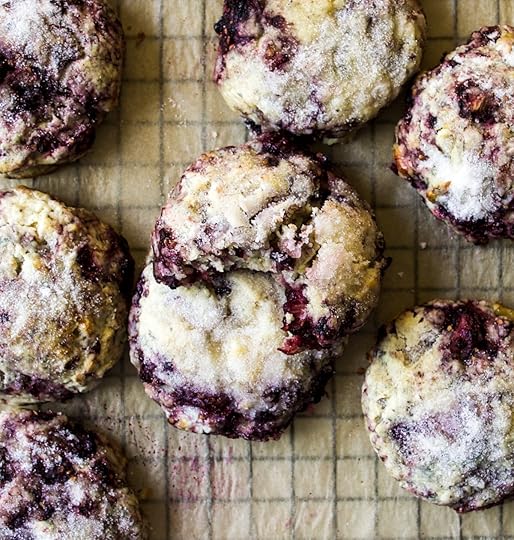 Close-up overhead shot of warm,freshly baked blackberry sconeswith a sweet sugar topping on a cooling rackor parchment paper, one scone broken opento show its tender crumb and juicy purple berries,homemade scone recipe from DisplacedHousewife.