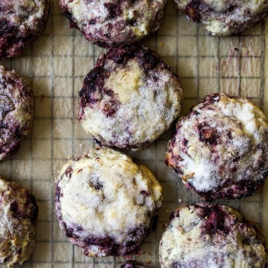 Overhead view of a batch offreshly baked blackberry sconeswith a sparkly sugar topping, restingon parchment paper, showing therich purple of the berries and golden crust,homemade scone recipe from DisplacedHousewife.
