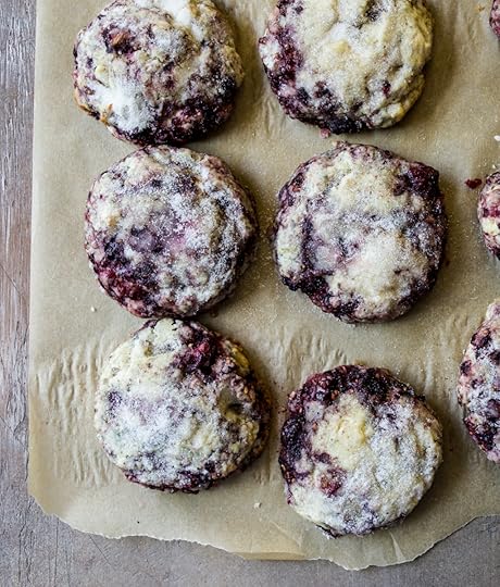 Overhead shot of a batch offreshly baked blackberry sconeswith a glistening sugar top, arrangedon parchment paper on a wooden surface,showcasing the juicy berries and tender crumb,homemade fruit scone recipe from DisplacedHousewife.