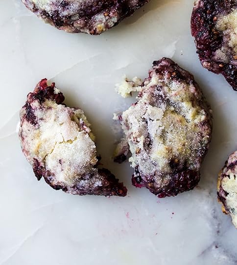 Close-up overhead shot of a freshly bakedblackberry scone broken in half, revealingits fluffy, tender interior, juicy purple berries,and glistening sugar crust, on a white marblesurface, homemade scone recipe from DisplacedHousewife.