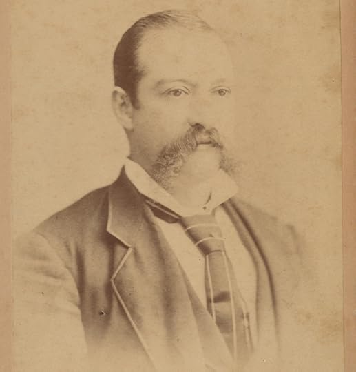 Sepia toned, head-and-shoulders portrait of an older William Kennoch. His hair is slicked back and his hairline has receded. He is wearing a suit and tie with a high white collar.
