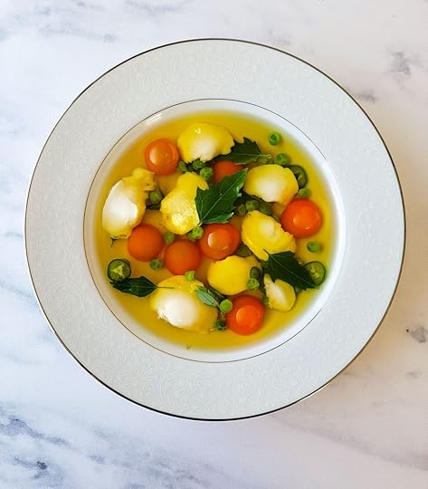 A bowl of clear fish soup with walleye cheeks and cherry tomatoes.