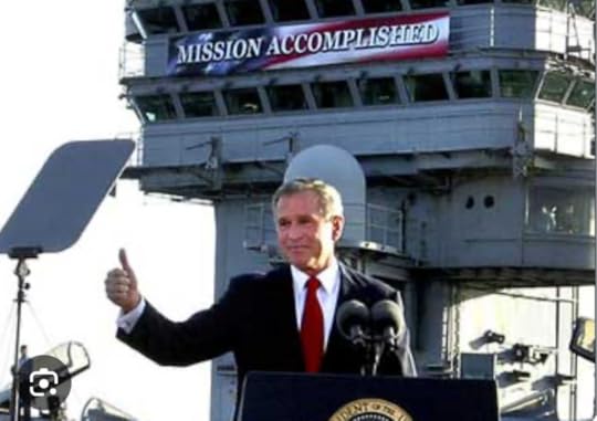 George W. Bush standing in front of a Mission Accomplished banner. 