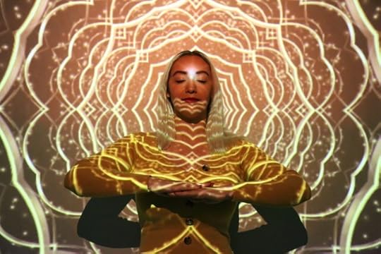 A woman sitting in lotus position within a projected mandala. Engaging active conscious awareness.