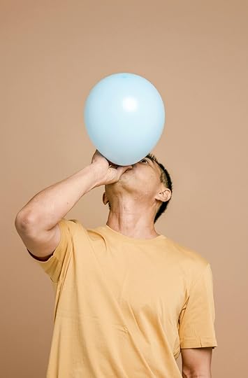 A man with his head tilted back as he blows up a single blue balloon.